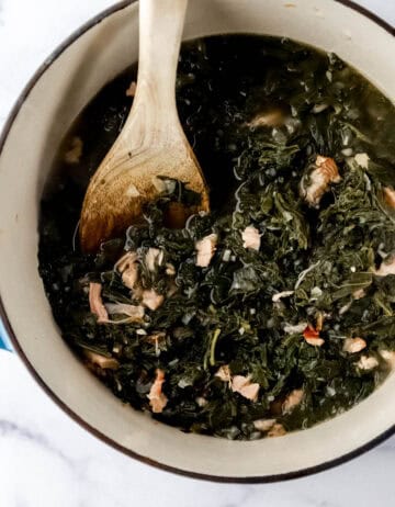 Finished greens in dutch oven with wooden spoon.