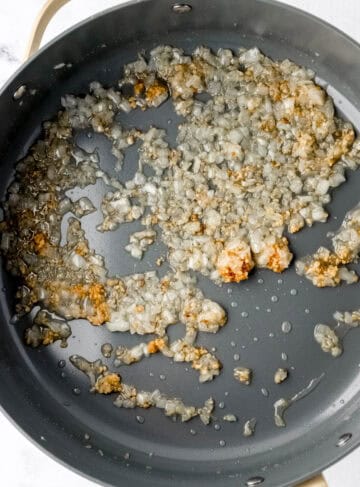 Overhead view of oil, onion, and garlic in skillet.