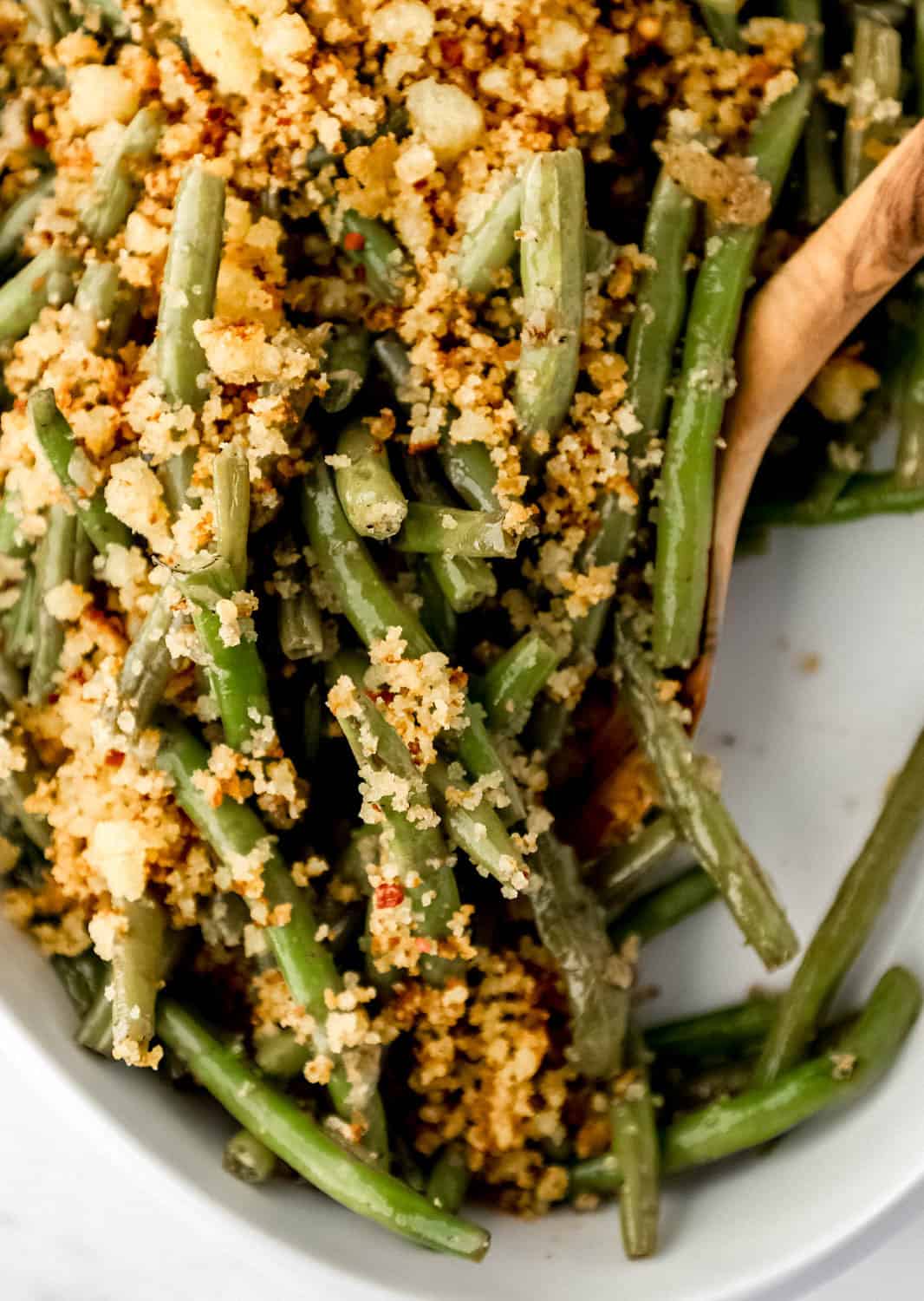 Close up view of finished green beans with wooden spoon.