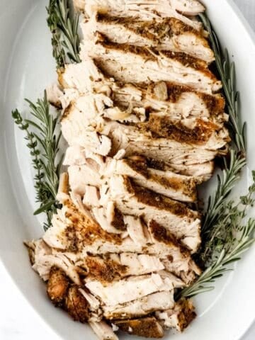 Close up view of finished turkey breast sliced in white dish.