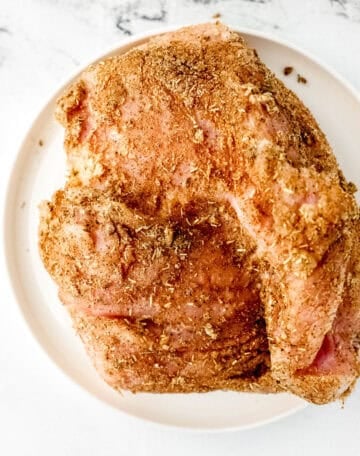 Buttered and seasoned turkey breast on white plate.