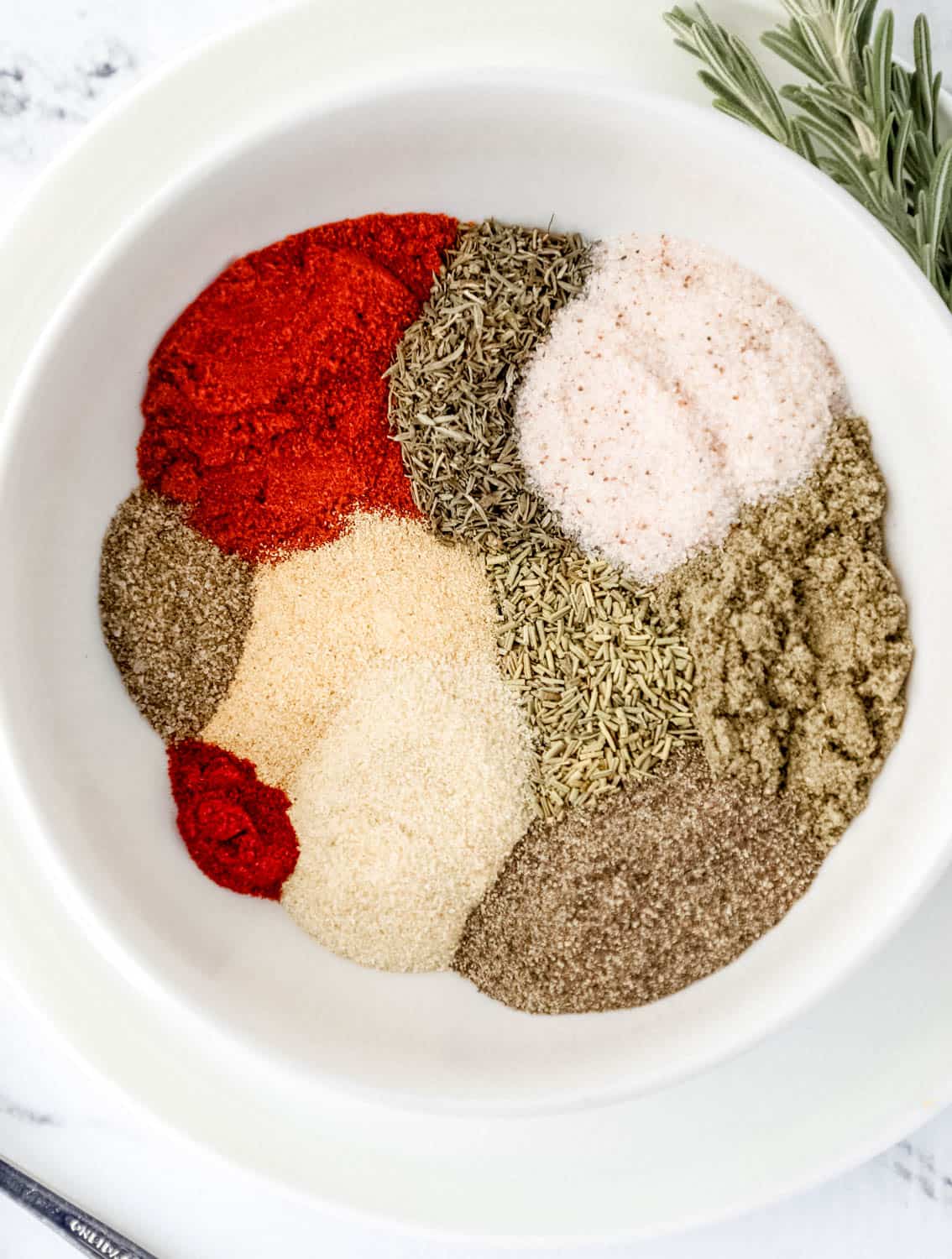 Spices needed to make seasoning blend in a white bowl.