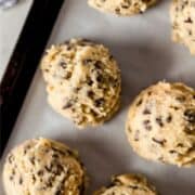 Close up view of cookie dough on parchment line sheet pan on pin with text overlay.