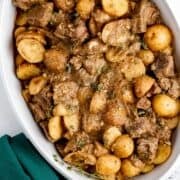 Close up overhead view of finished steak and potatoes in white serving dish.