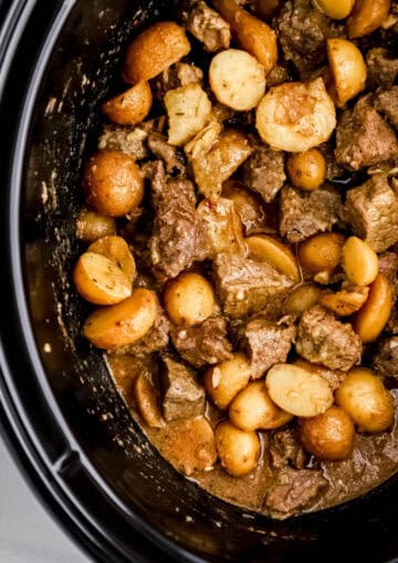 Close up view of finished steak bites in black slow cooker.