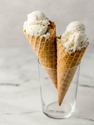 Close up front view of two vanilla ice cream cones in a glass.