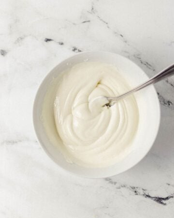 Overhead view of melted white chocolate in bowl with spoon.