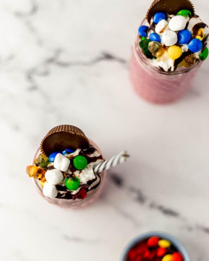 Overhead view of two finished shakes by a small bowl of candy.