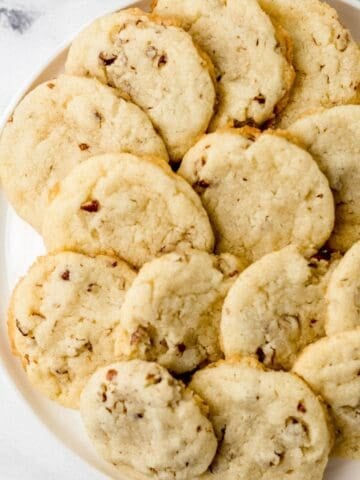 Overhead view of finished pecan sandies on a white plate.