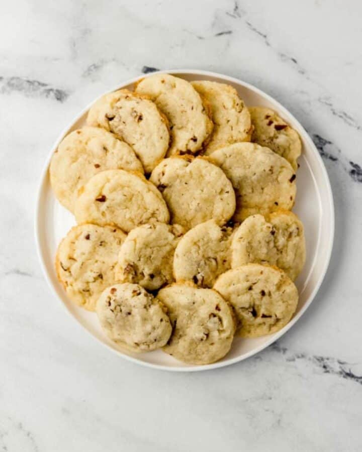 Overhead view of finished cookies piled on a large white plate.